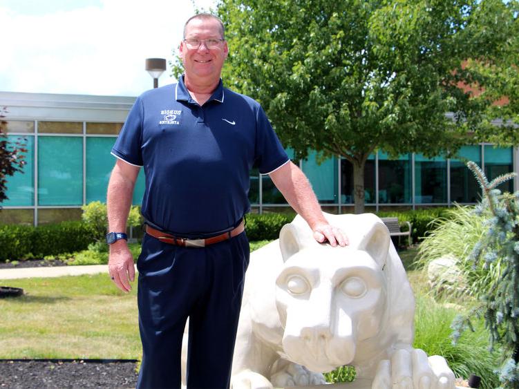 New head golf coach at Penn State DuBois John Schneider stands with the Lion Shrine on campus.